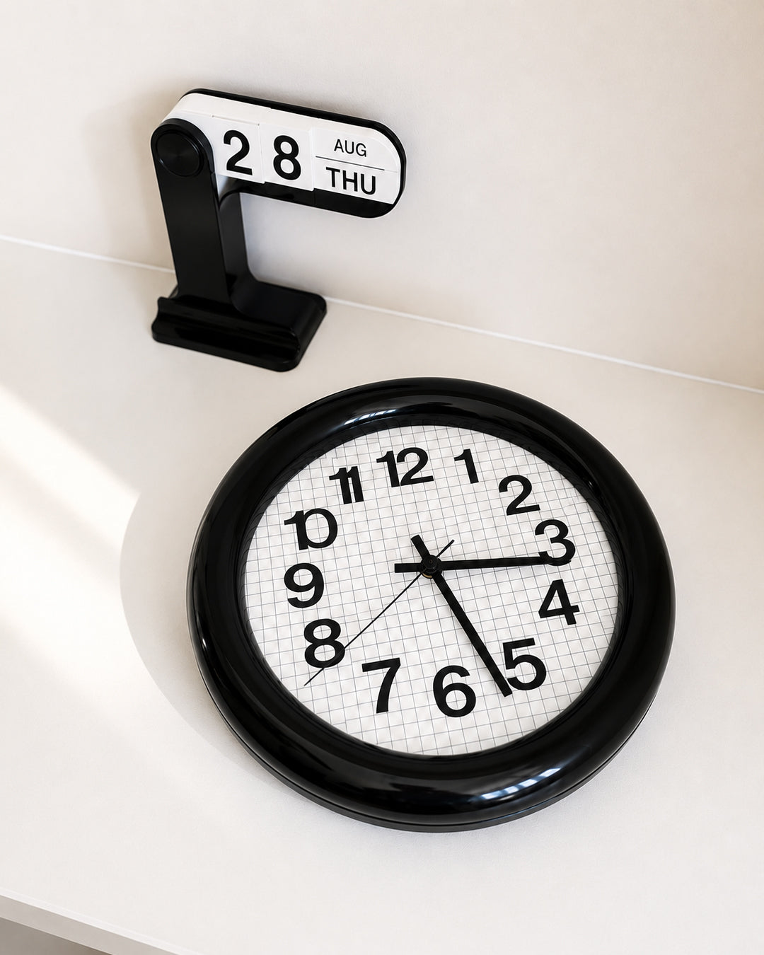 bold grid wall clock with thick round frame in black - front view product photo