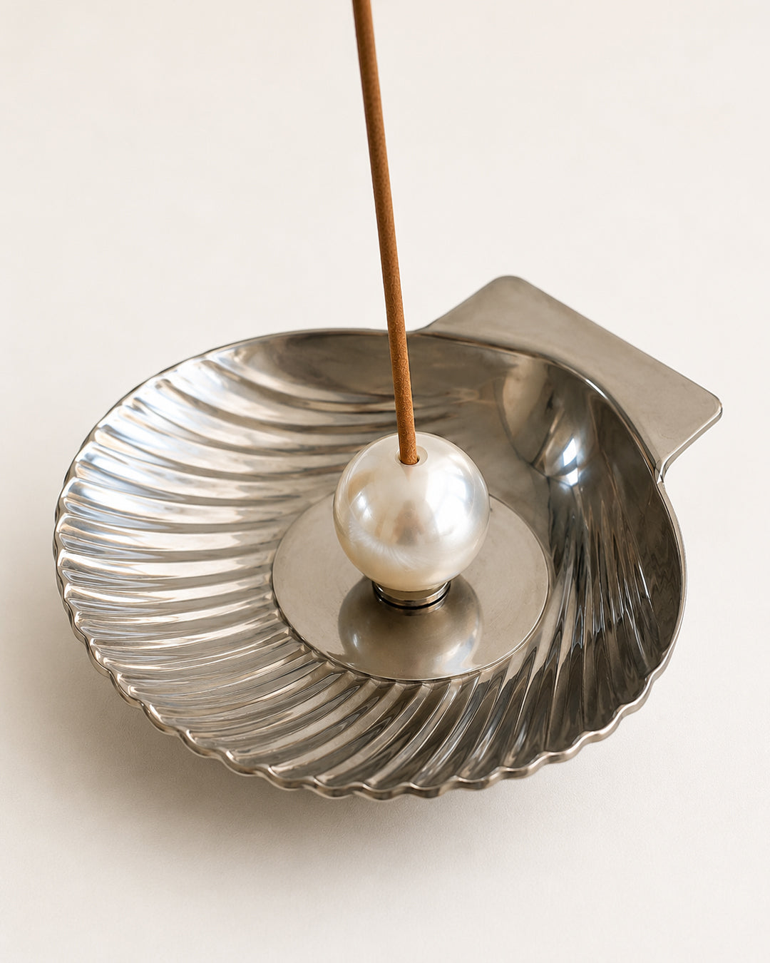 shell incense tray shown holding a lit incense stick