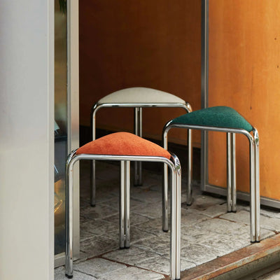 White, green, and orange triangle stacking stools in a wood-paneled doorway nook