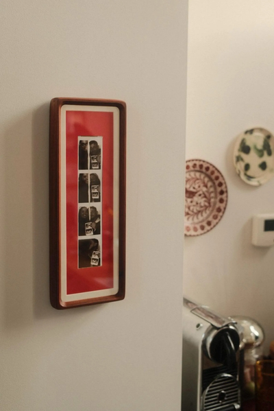 Red wood photo strip frame with key hooks mounted in a hallway