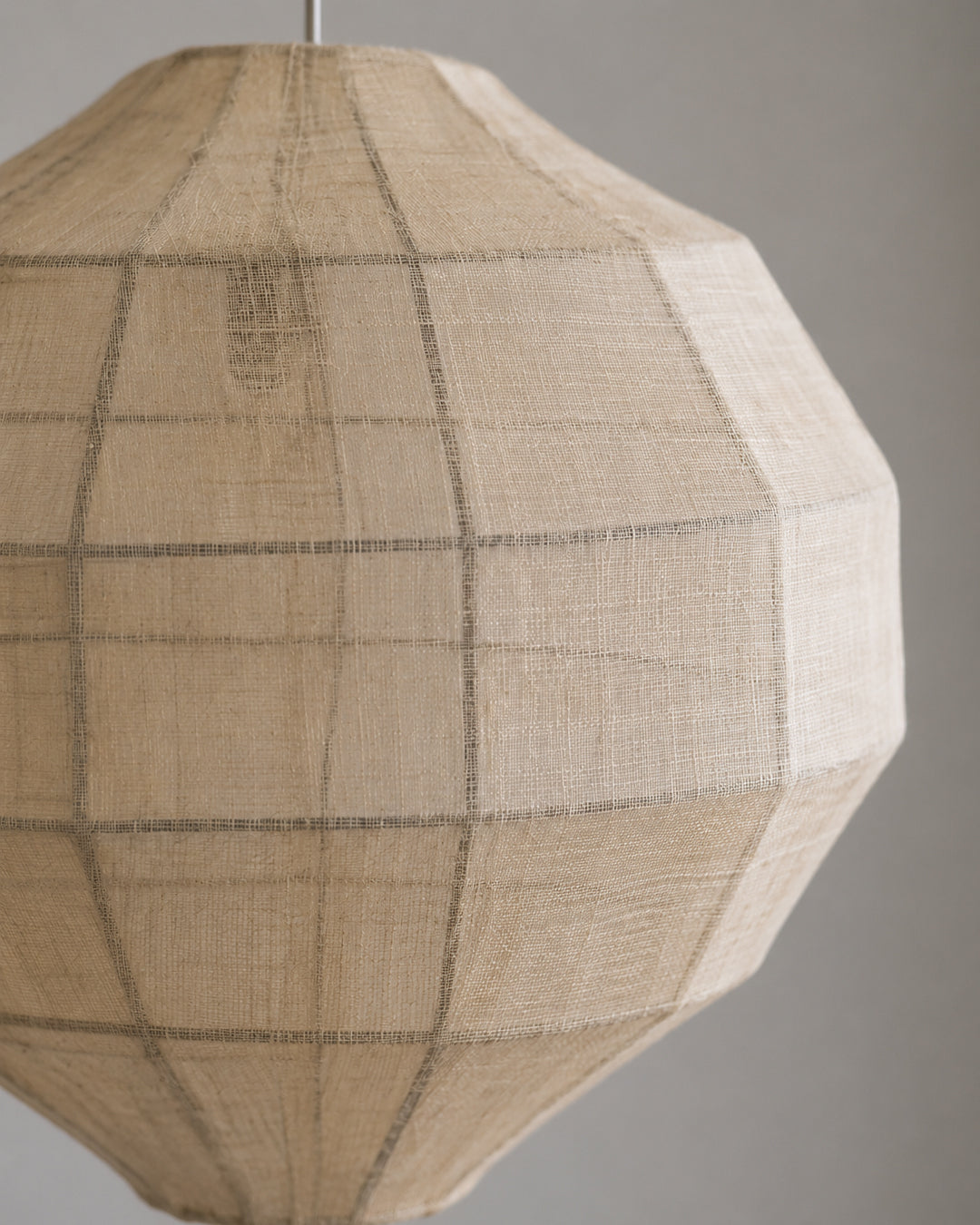 Plant fiber pendant light illuminated, showing warm glow